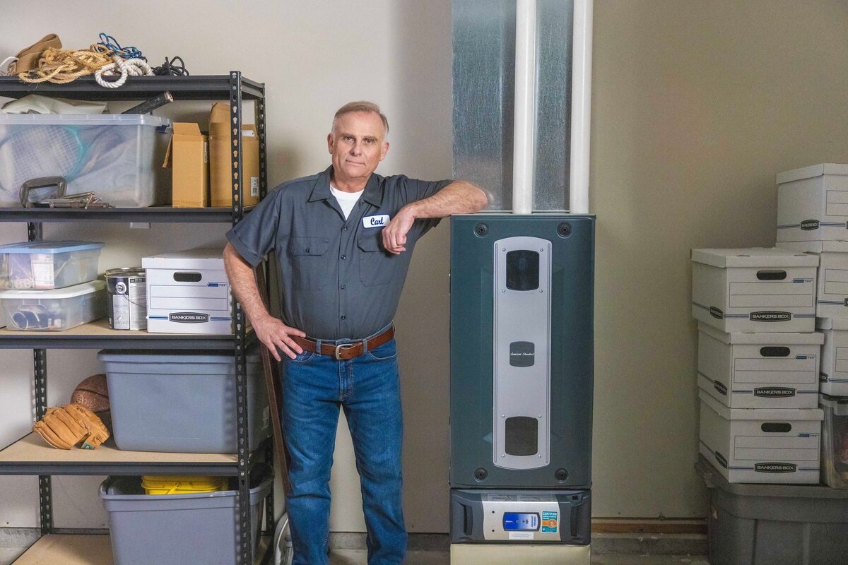 hvac technician posing with a furnace