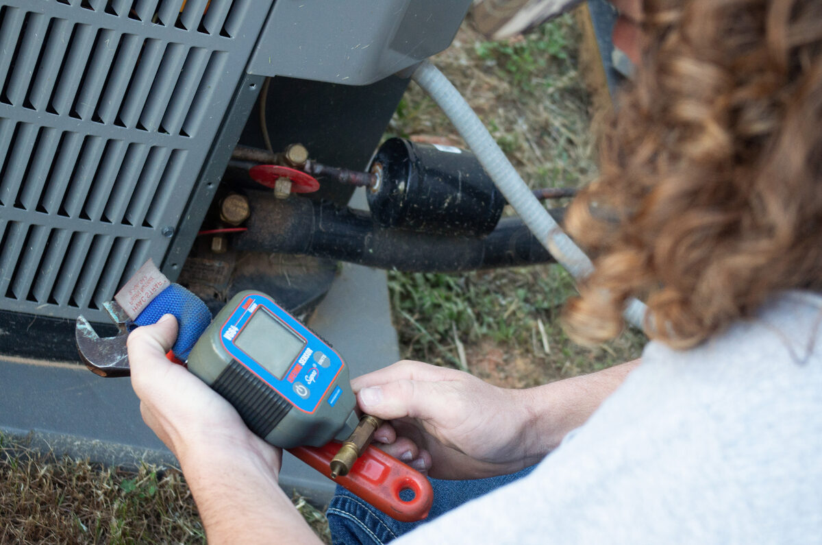 HVAC technician testing an outdoor air conditioning system