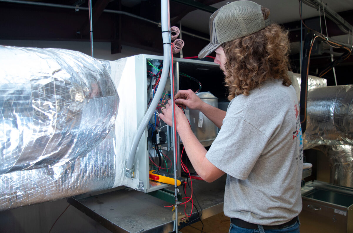 HVAC technician working on electrical components of a heating and cooling system