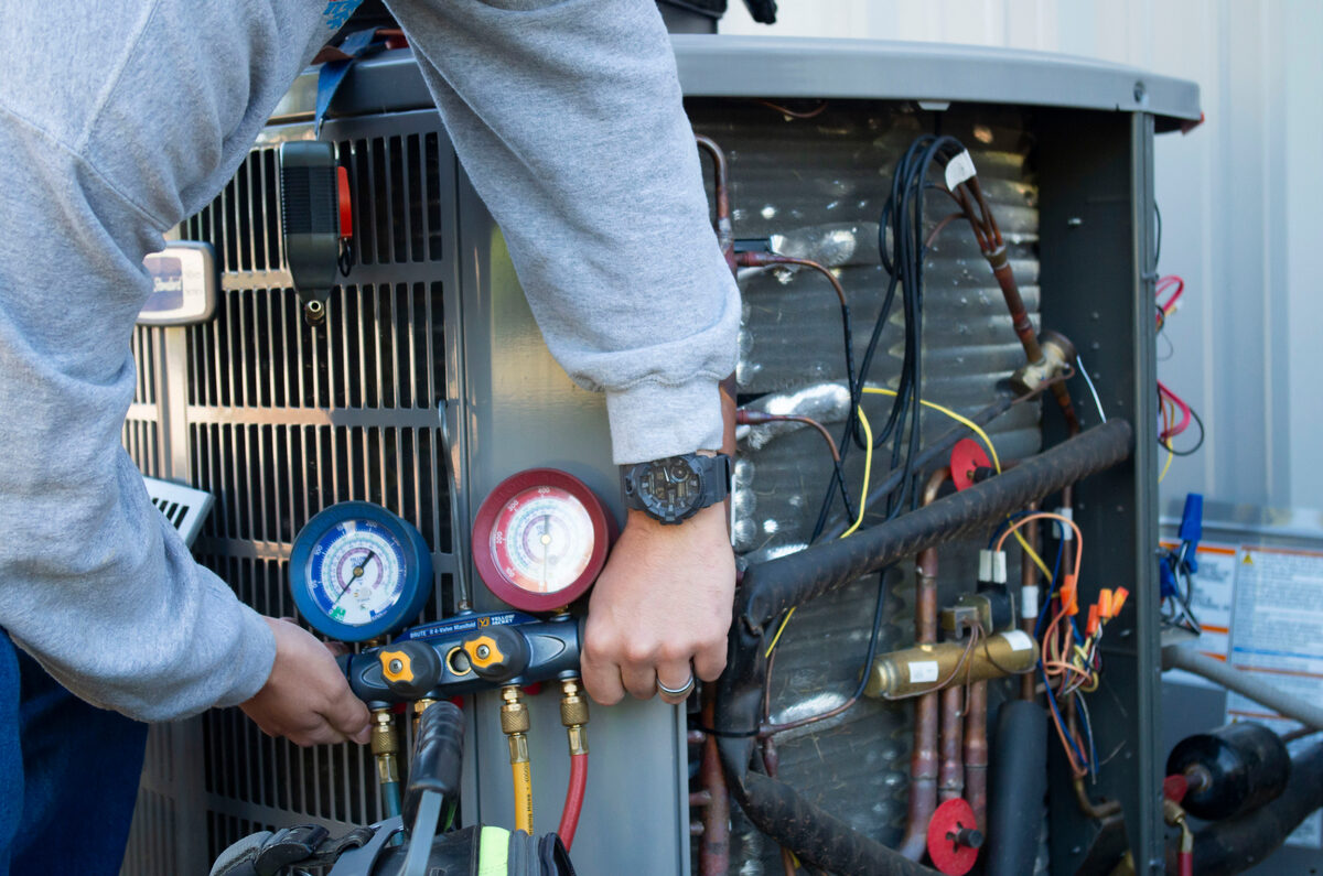 HVAC technician inspecting the inside of an air conditioning unit